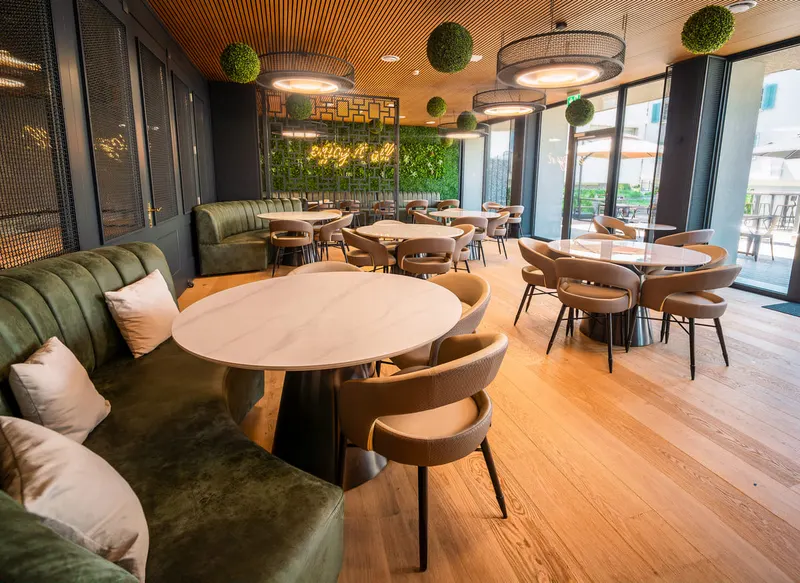 Restaurant im Berg & Berg Hotel Kerns mit grüner Sitzbank, runden Tischen und Holzboden